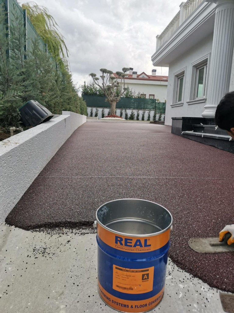 Taş halı uygulaması — reçine bağlı agreganın malta ile serilmesi